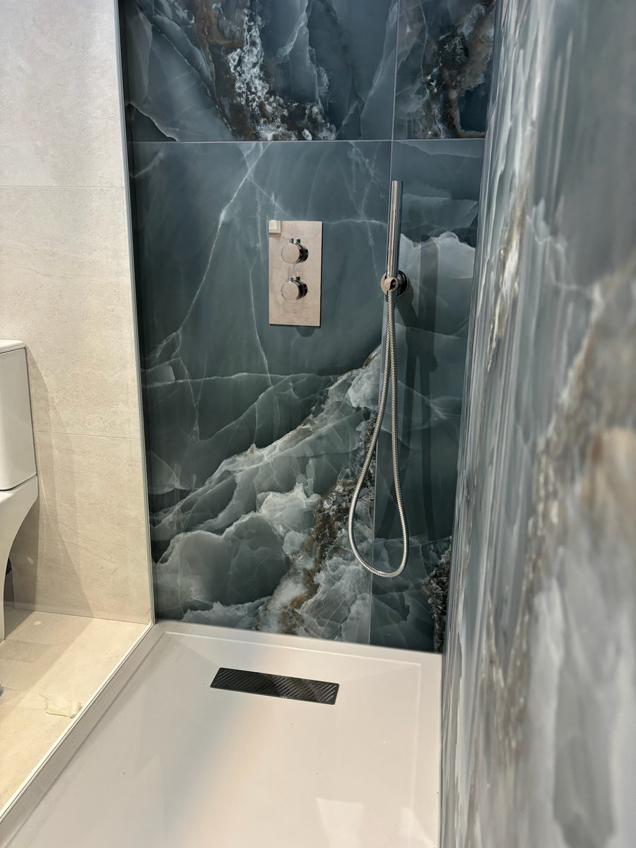 Green onyx tiles in matt in the shower area with a beige stone effect wall and floor tile in the rest of the room